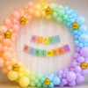 Pastel rainbow birthday decoration with balloon arch, gold star foil balloons, fairy light curtain and happy birthday banner.