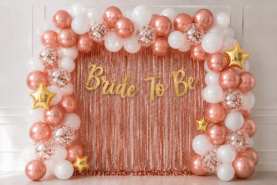 Bride to be rose gold and white balloon decoration with rose gold foil curtain, gold banner, confetti balloons and gold star foil balloons for bridal shower party.