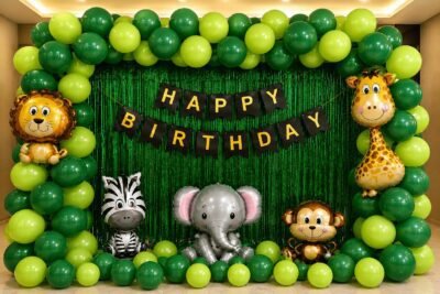 Jungle theme birthday decoration with green balloon arch, animal foil balloons, green foil curtain and happy birthday banner.