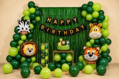 jungle-theme-49-optimized Jungle safari theme happy birthday decoration with green balloons, animal foil balloons, fringe curtain and birthday banner for kids party setup.
